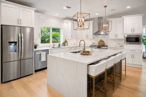 Modern kitchen remodel in Winter Park FL with white shaker cabinets, quartz waterfall island, gold fixtures and pendant lighting