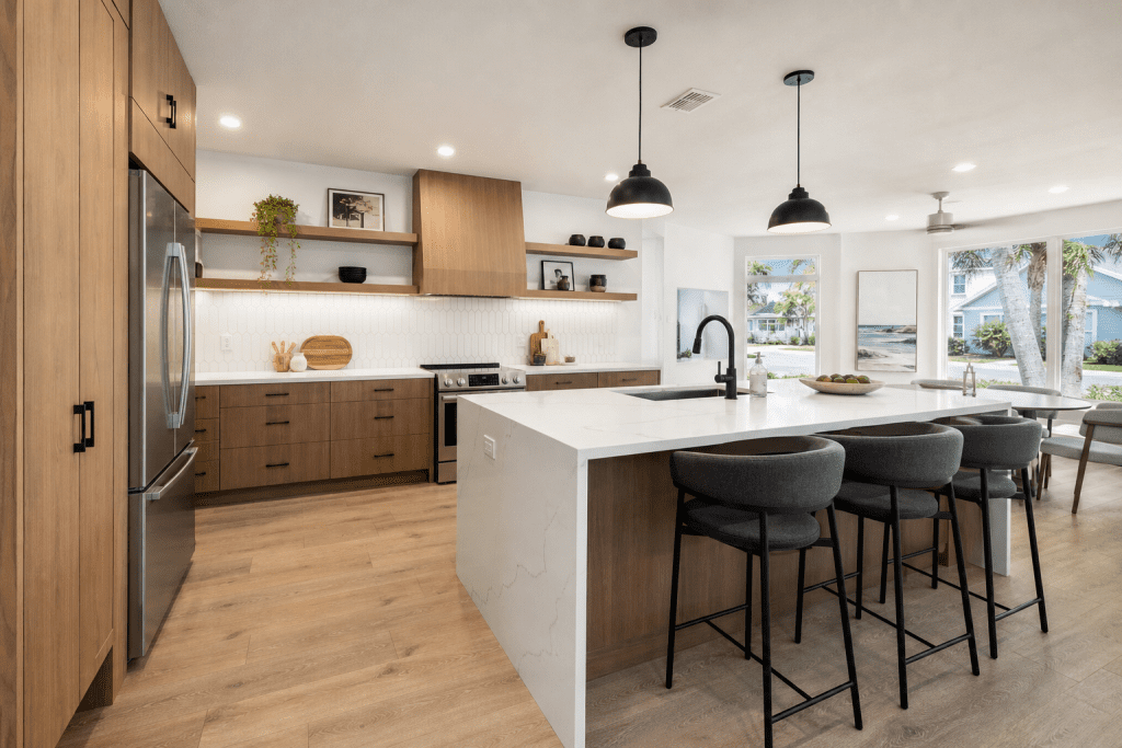 Warm wood kitchen cabinets with quartz waterfall island, matte black fixtures, and open shelving in a remodeled Winter Park Florida home